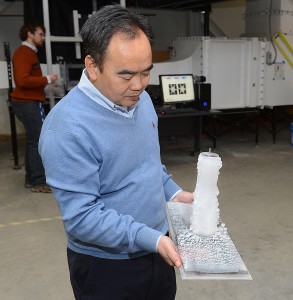 Iowa State's Hui Hu examines ice on a test model taken from the university's Icing Research Tunnel. The refurbished tunnel, which has been fully functional for a few weeks, is in the background. Photo by Bob Elbert.