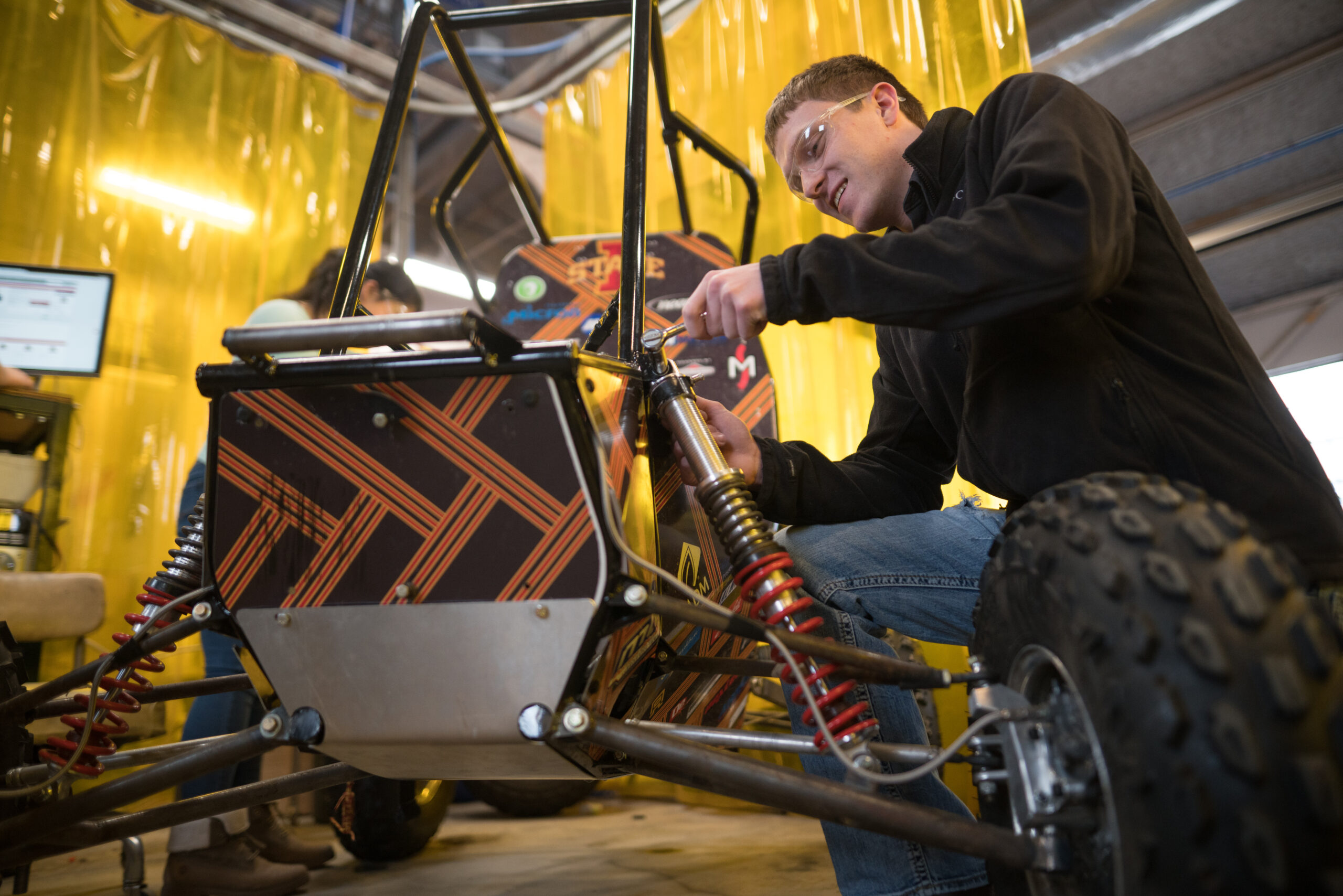 Two students working on a vehicle for their student organization.