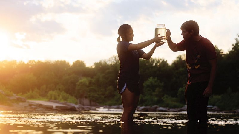 Students collecting water samples from river.