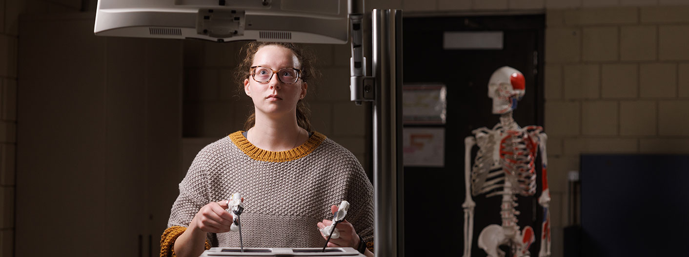 student at computer with human skeleton in background