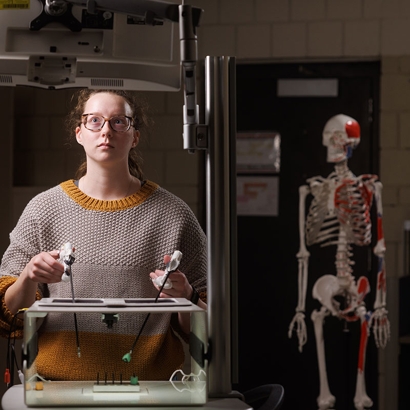 student at computer with human skeleton in background