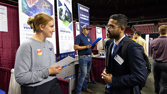 student interacts with prospective employer at career fair
