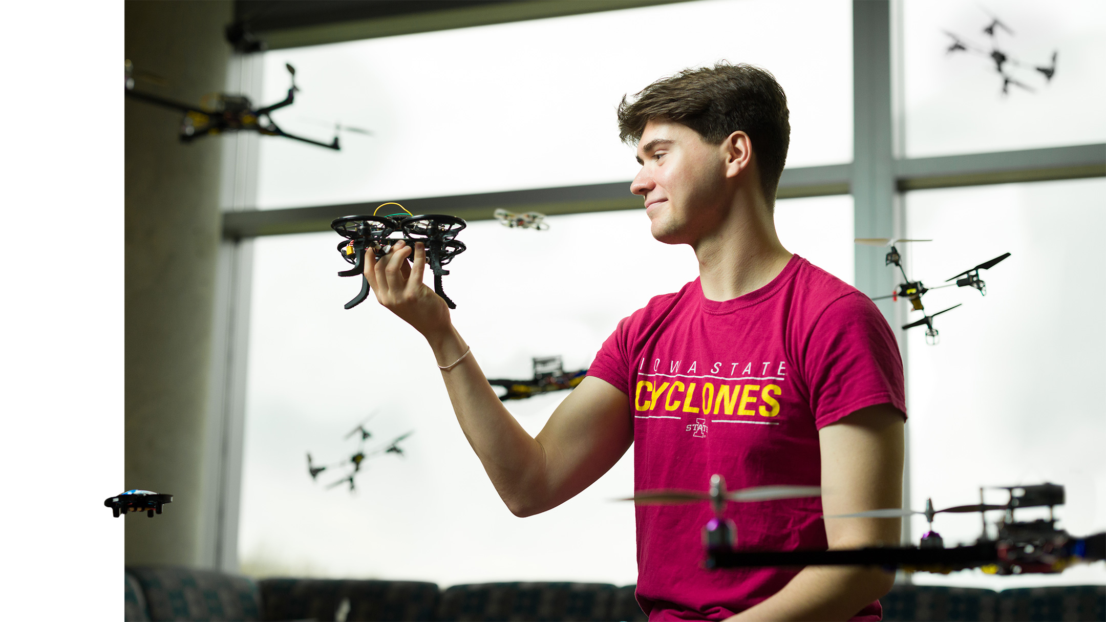 Student examines drone technology while surrounded by drones in flight
