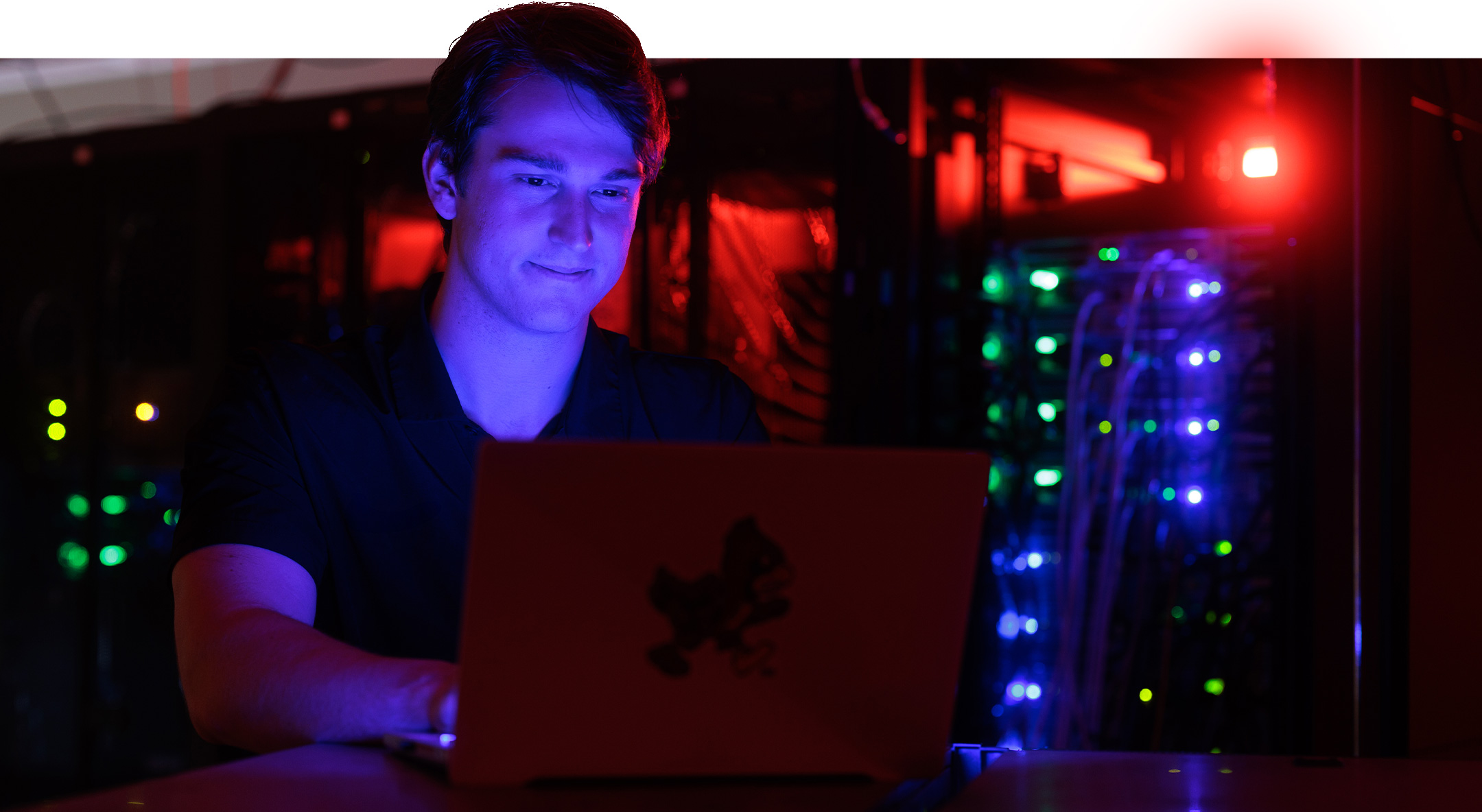 Student works on security code while surrounded by computing systems
