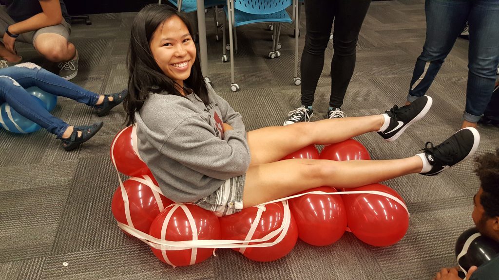 student sits on seat made of balloons