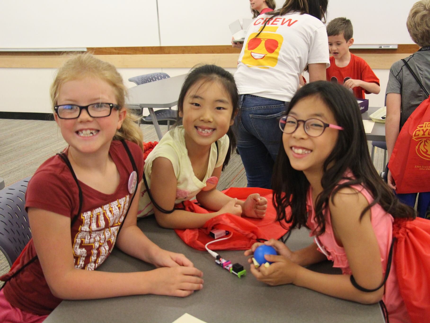 Three school-aged girls smiling while attending a STEM workshop.