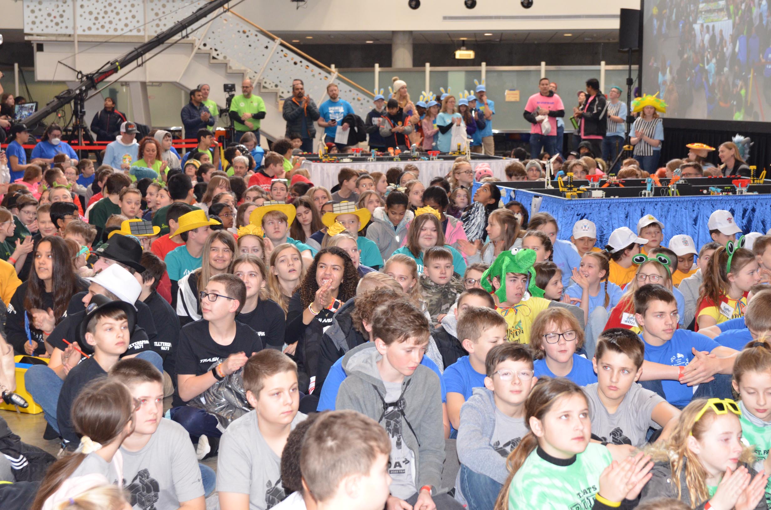 Crowd of youth seated on floor at a STEM outreach event.