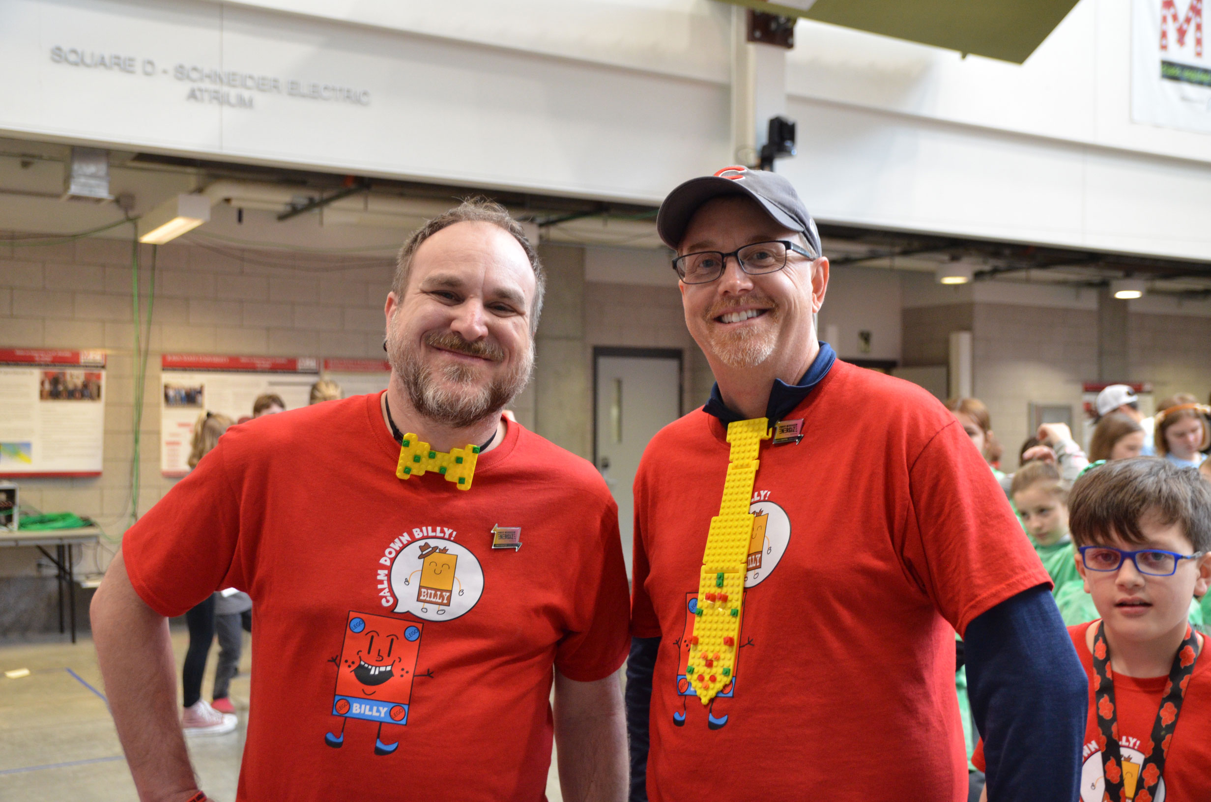 Two FIRST LEGO League coaches posing for the camera wearing neckties made out of LEGO