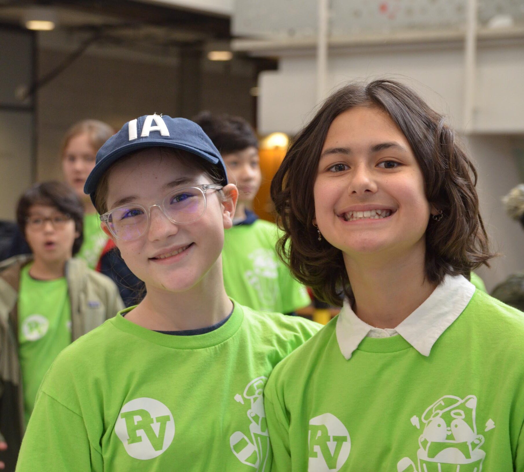 Two youth in green shirts smiling.